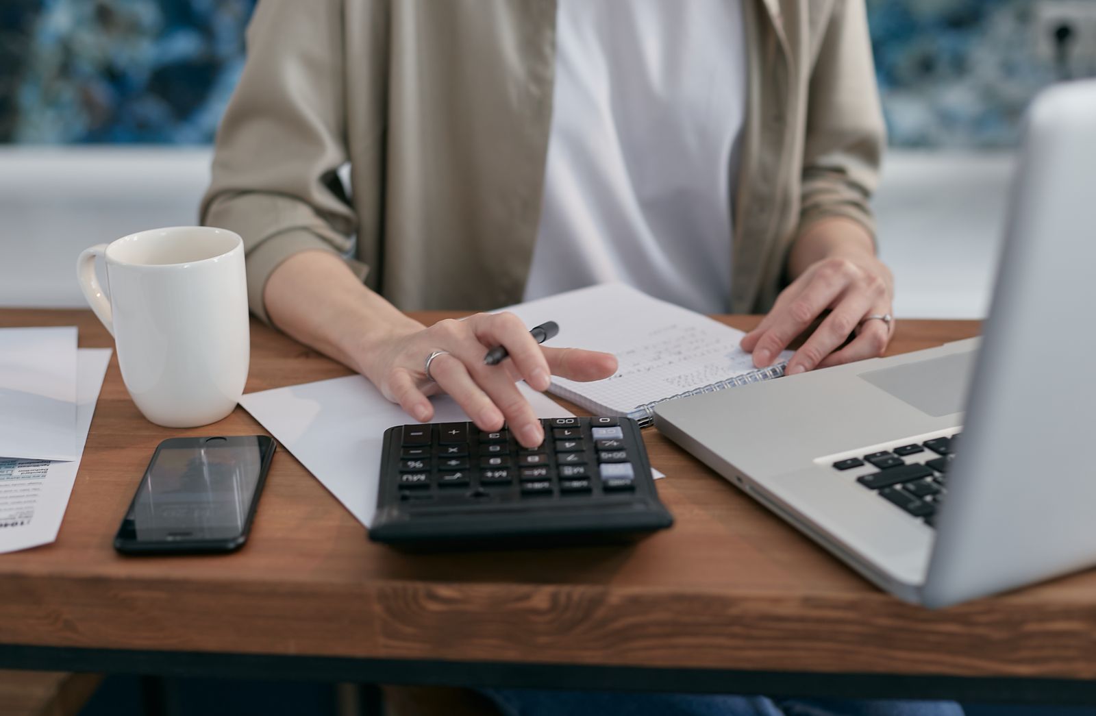 small business owner reviewing a budget and invoice on paper alongside a laptop while planning a website investment