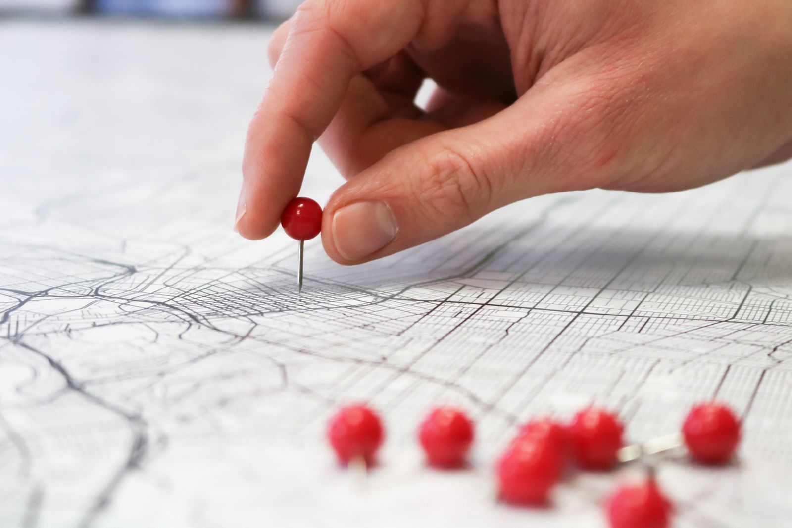 close-up of a hand placing a red pin on a paper map, representing service-area targeting for local SEO in Ontario towns like Chatham-Kent