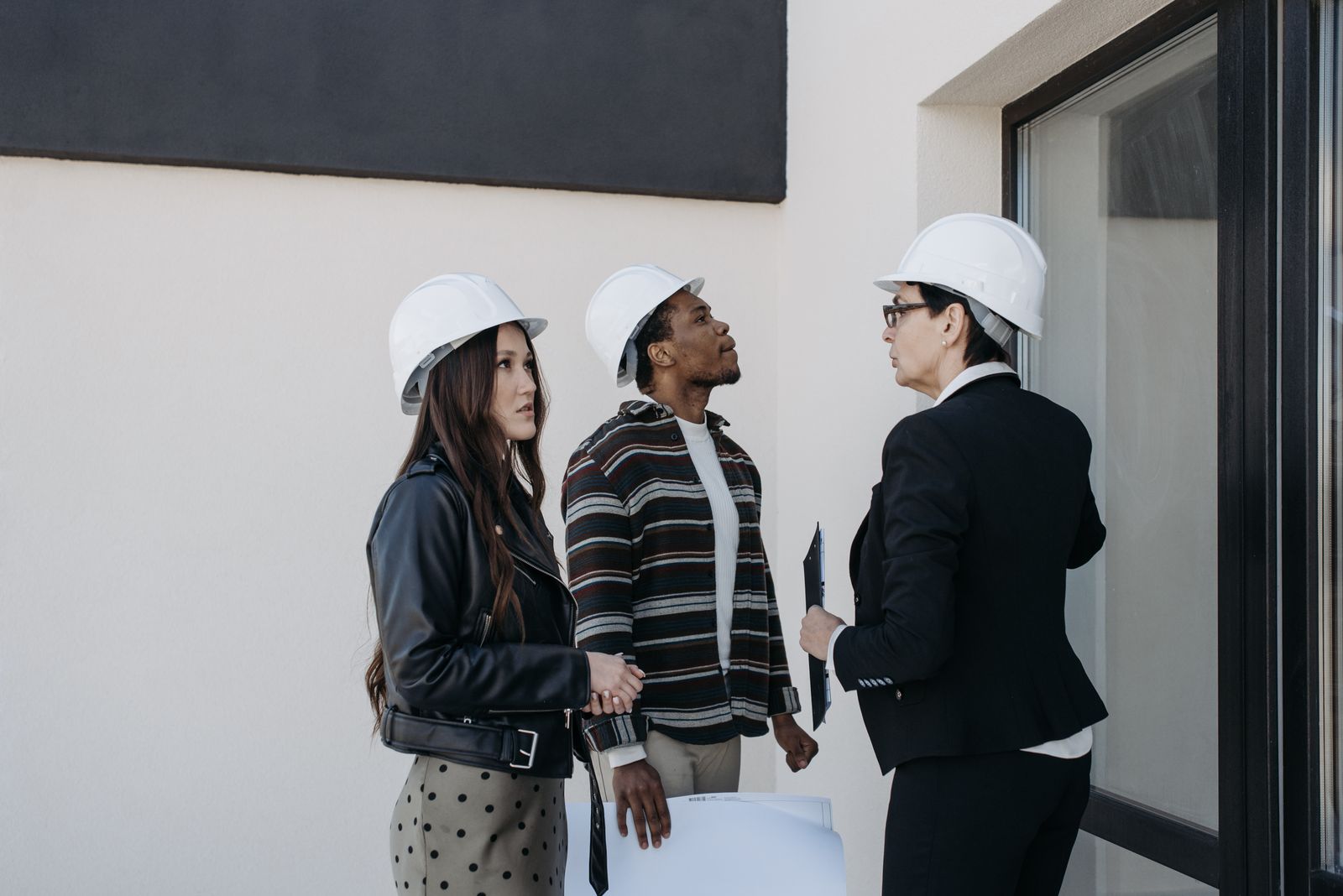 Contractors in hard hats reviewing property repair plans together on-site, similar to a roofing consultation with a homeowner after storm damage